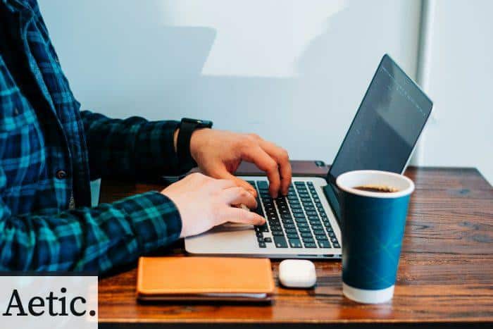 person wearing blue and green plaid collared button-up long-sleeved shirt sitting while using MacBook Pro