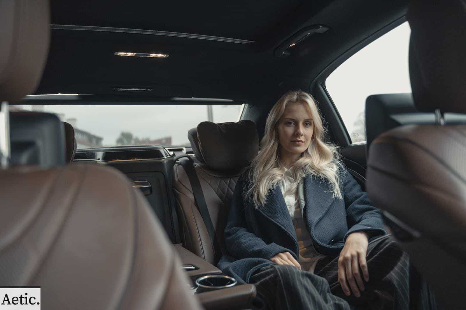 Woman in Blue Coat Sitting on Back Seat of a Car