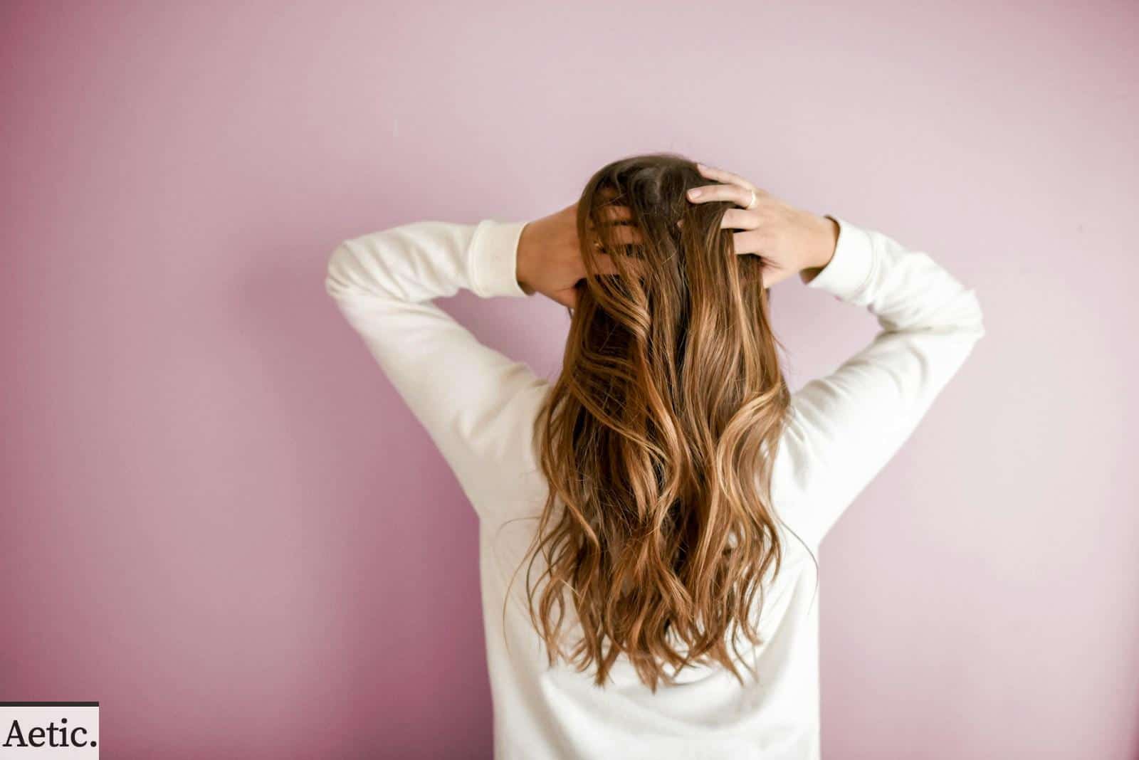 woman in white long-sleeved shirt standing in front of pink wall