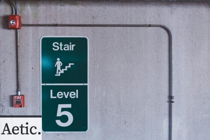 A fire alarm and stair sign on level 5 in an industrial indoor setting.