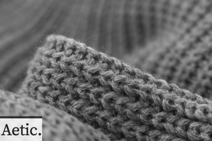 Macro black and white photo showcasing the intricate texture of grey knitted wool fabric.