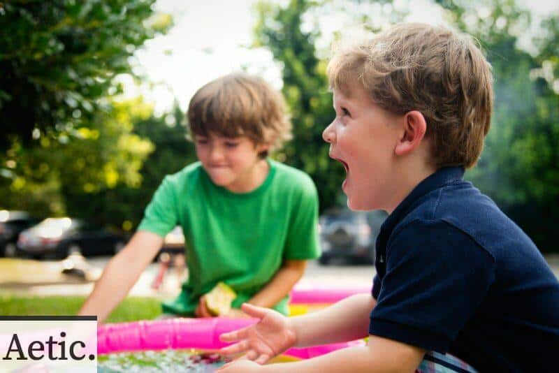 boy in blue shirt screaming near boy in green crew-neck shirt